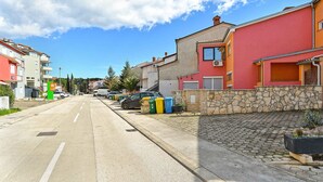 Una calle residencial con casas, coches aparcados y cielo despejado.