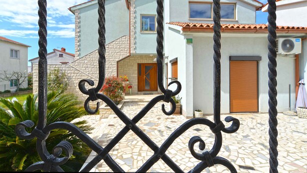 A building with a stone facade, a tiled patio, and a wooden door. - Holiday apartment with air conditioning (Pula)