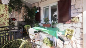 A small patio with a table and chairs, surrounded by potted plants and a stone wall. - Holiday apartment with air conditioning (Premantura)