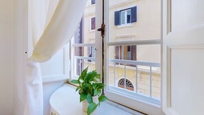 Une pièce avec une fenêtre, une plante en pot et une vue sur les bâtiments environnants.