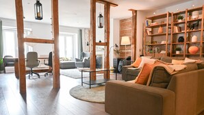 Un salon moderne avec un plancher en bois, un ensemble de canapés, une table basse et une bibliothèque.