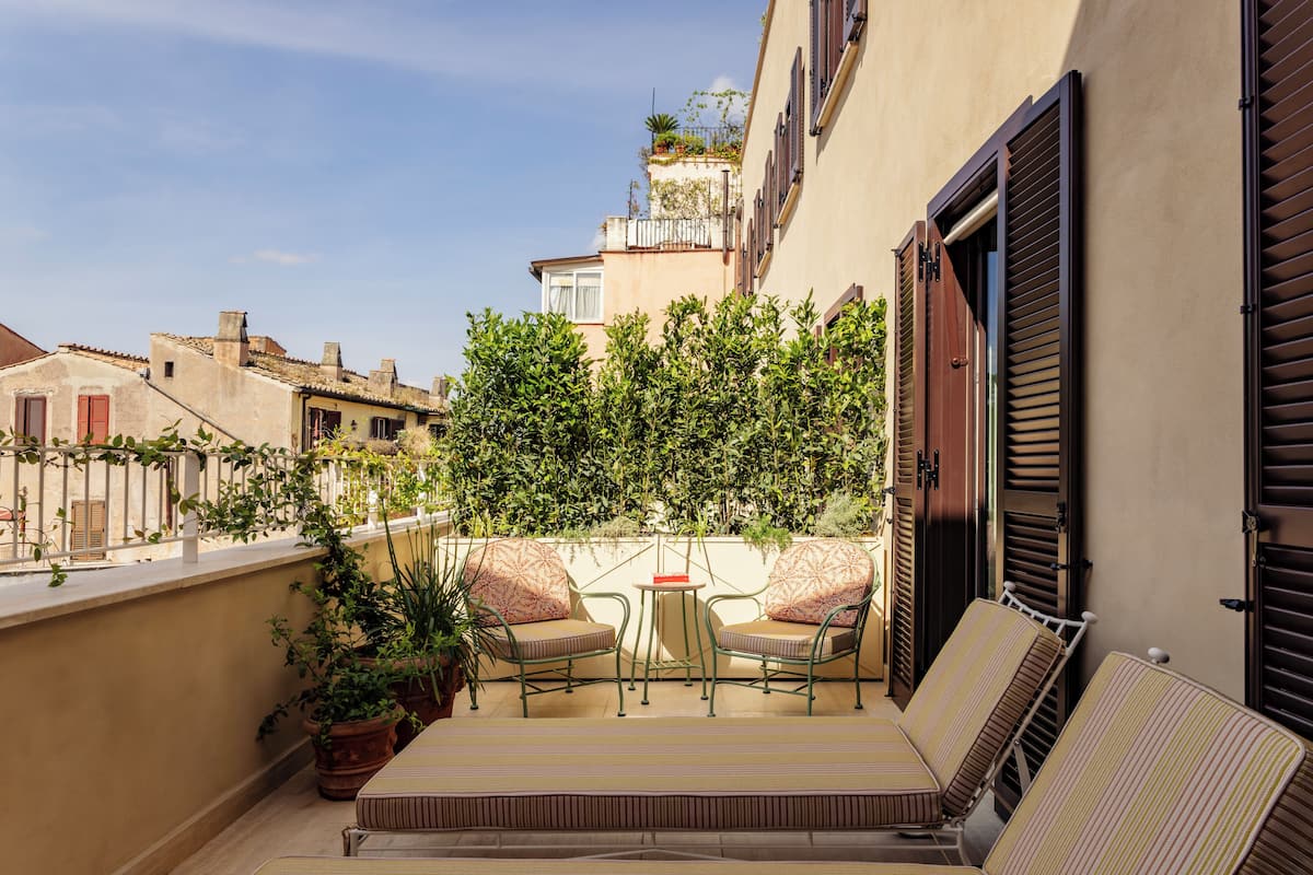 Un balcon avec une table et des chaises, des plantes en pot et un canapé.