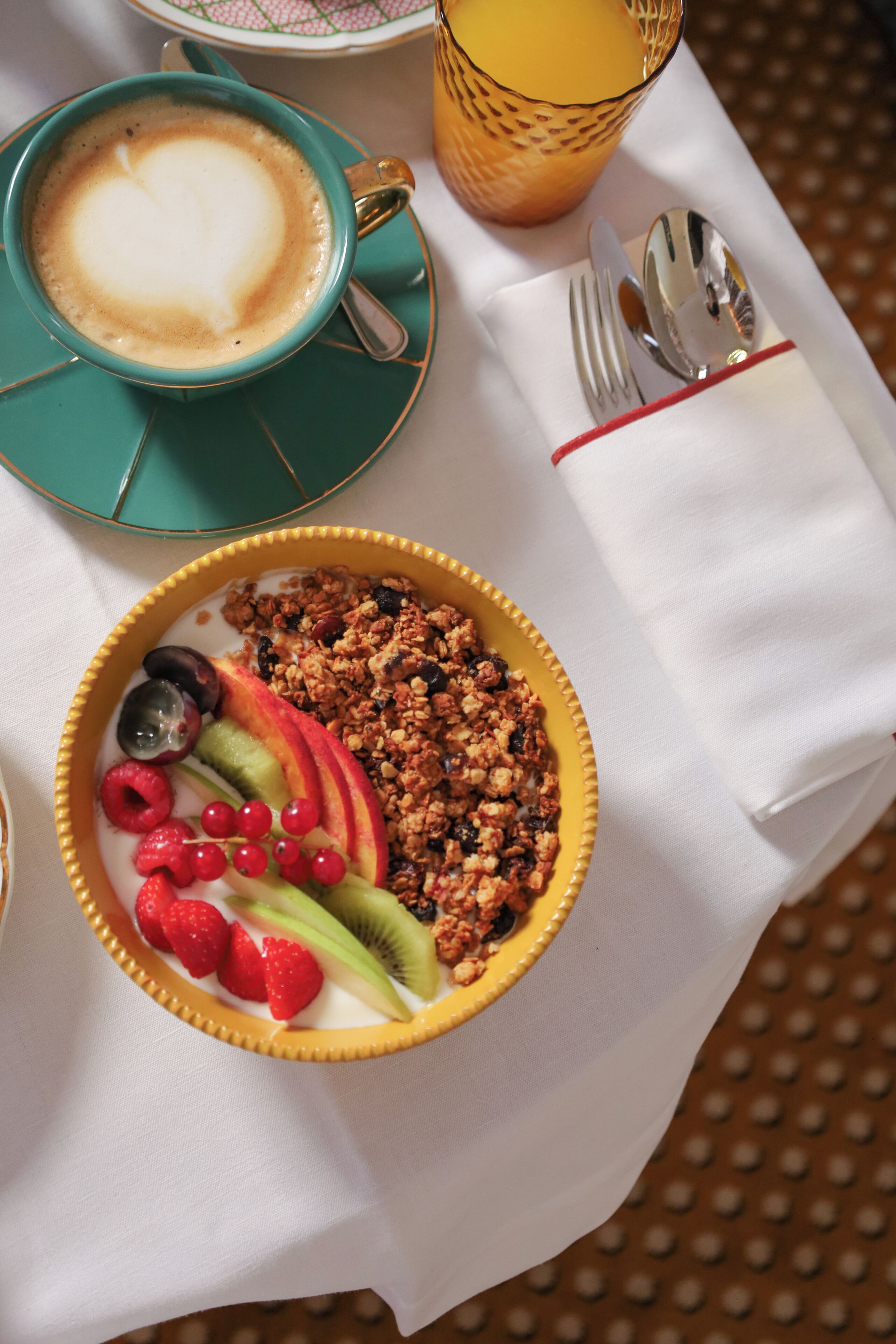 Una mesa con una taza de café, un frutero y una servilleta.