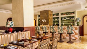 A dining area with striped upholstered seating, a bar with green shelves, and a patterned lamp. - Casa Monti Roma (Rome)