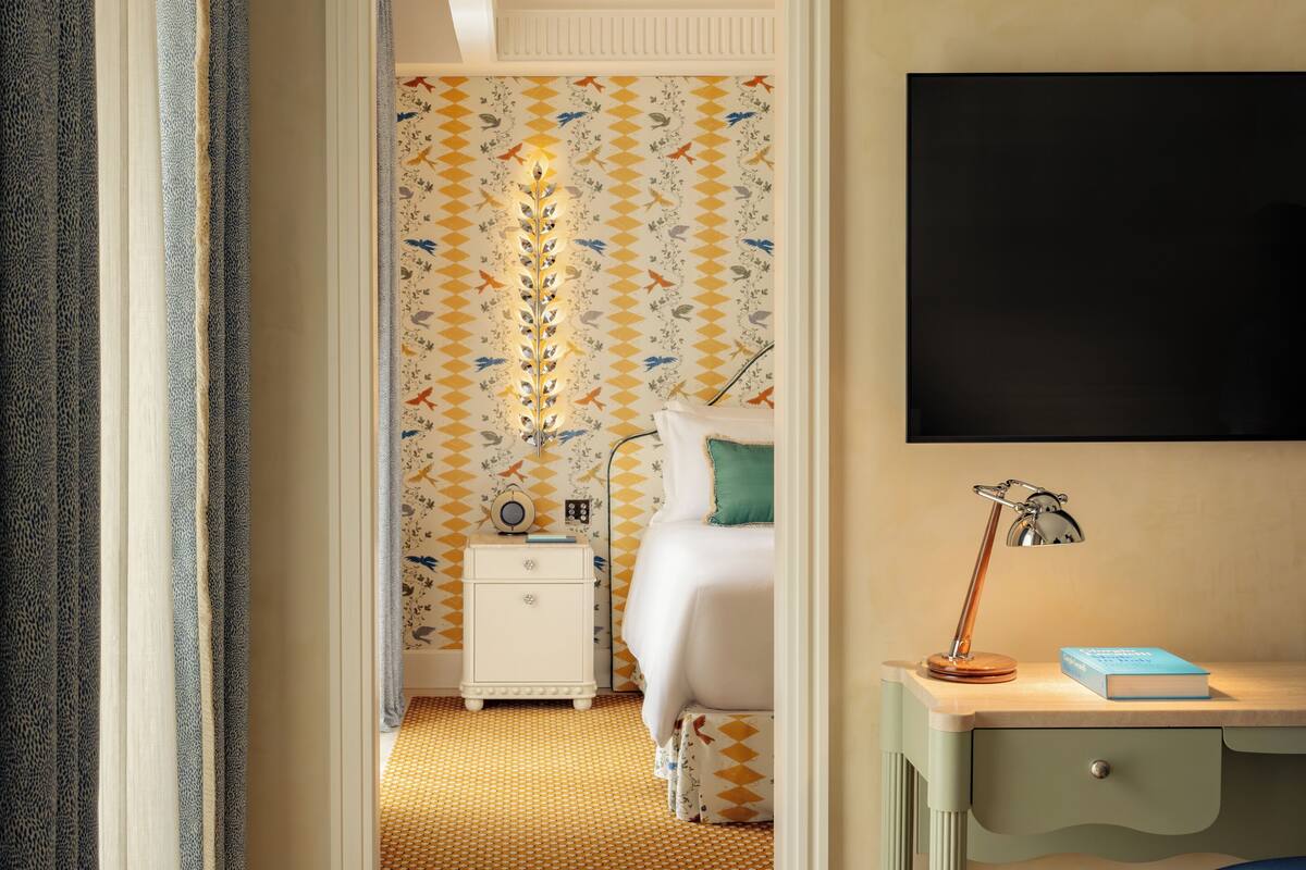 Une chambre d’hôtel comprenant un lit, une table de chevet, une lampe et un bureau avec une chaise.