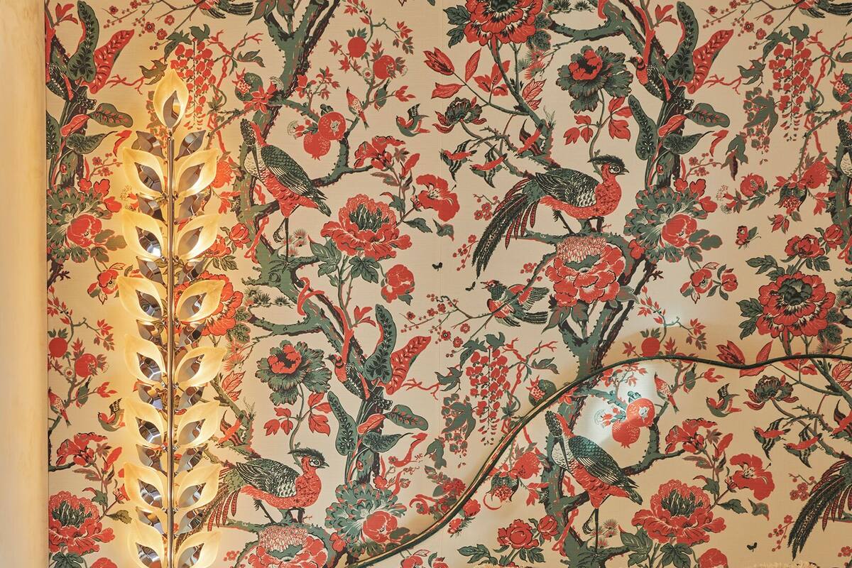 Une chambre à coucher avec un papier peint à motifs floraux, une table de chevet et un lit avec un oreiller.