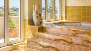 Une salle de bain spacieuse avec une grande baignoire, un vase décoratif et une plante en pot près de la fenêtre.