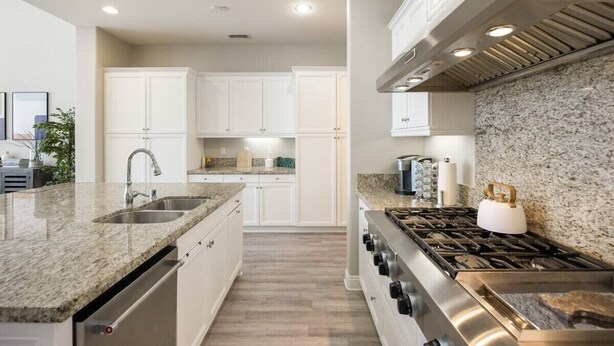 A modern kitchen with granite countertops, stainless steel appliances, and white cabinetry. - PGA West Getaway with Pool & Fire Pit (La Quinta)