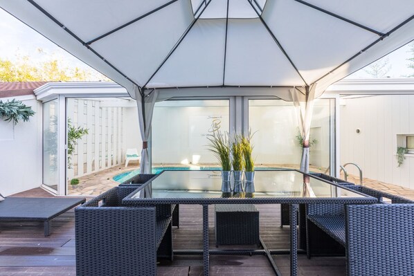 Un espace extérieur abrité comprenant une piscine, des chaises longues et une table.