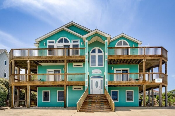 A multi-story building with a central entrance, balconies, and a wooden deck.