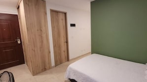 Ein Zimmer mit einem Bett, einer Holztür und einer grünen Wand.