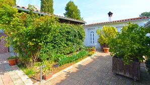A courtyard with a tiled roof, potted plants, and a brick wall. - Holiday apartment with air conditioning (Bale)