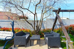 An outdoor seating area with wicker furniture and a swing set.