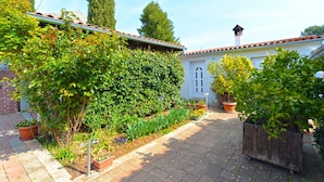 A courtyard with a tiled roof, potted plants, and a brick wall.