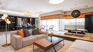 A modern living room with a sofa, coffee table, and a dining area with a table and chairs. - JAPAVISTA Xenith Premium (Osaka)