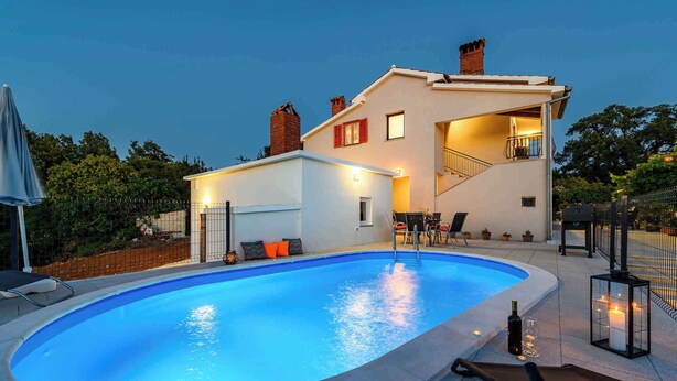 Une maison moderne dotée d’une piscine, d’un espace salon extérieur et d’un escalier menant à un étage supérieur.