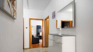 Un couloir avec une armoire blanche, un miroir et un tableau accroché au mur.