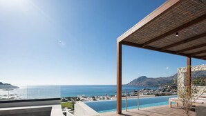 A modern outdoor pool area with a clear view of the sea and distant hills. - Villa Hestia - 6 Bedroom Luxury Villa With Seaview (Agios Vasileios)