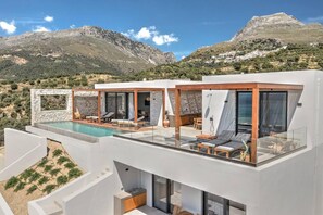 Une villa moderne dotée d’une piscine sur le toit, de grandes fenêtres et offrant une vue sur les montagnes.