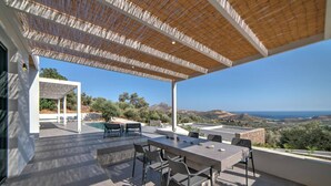 An outdoor patio with a table and chairs, a pool, and a view of the landscape. - Villa Chelidoni in Mariou (Agios Vasileios)