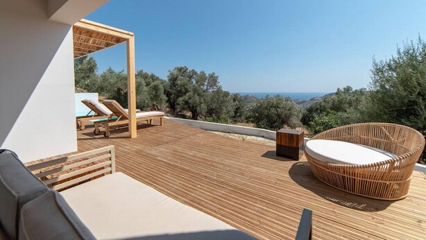 A wooden deck with a sofa, two lounge chairs, and a wicker chair. - Villa Mare in Mariou (Agios Vasileios)