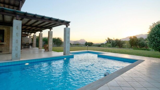 A swimming pool with a pergola and a covered patio area. - Villa Helios in Foinikas (Agios Vasileios)