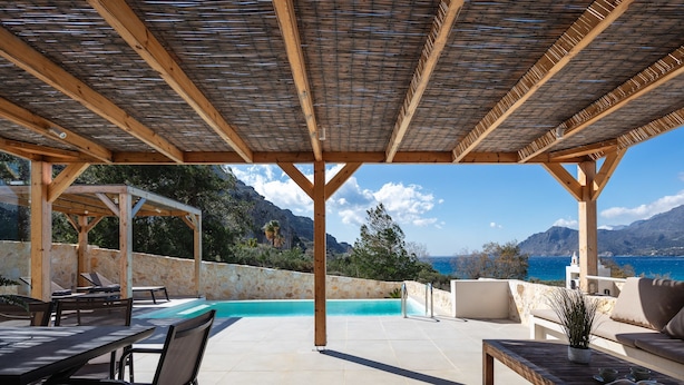 A covered outdoor area with a pool, wooden pergola, and seating. - Villa Petra in Plakias (Agios Vasileios)