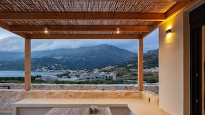 A covered outdoor seating area with a view of a mountainous landscape and a body of water. - Villa Petra in Plakias (Agios Vasileios)