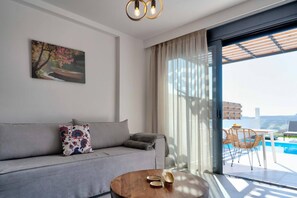 A modern living room with a sofa, a coffee table, and a painting on the wall. - Villa Iris in Mariou (Agios Vasileios)