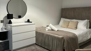 Ett modernt sovrum med en säng, ett sängbord, en spegel och en hängande lampa.