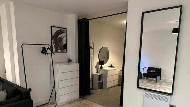 Ett modernt sovrum med en stor spegel, en garderob och ett skrivbord.
