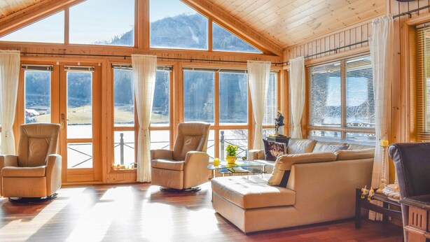 A spacious living room with a high ceiling, large windows, and a view of mountains. There are two armchairs and a sofa. - 4 bedroom cozy home in Farsund (Farsund)