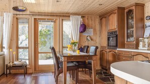 A wooden cabin interior with a dining area, kitchen, and a view of the outdoors. - 4 bedroom cozy home in Farsund (Farsund)