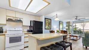 Una cocina moderna con una isla central, un comedor con sillas y vistas al exterior.