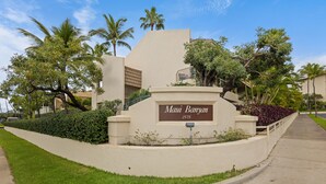 Letrero de 'Maui Banyan' con un césped cuidado y palmeras.