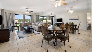 A spacious living room with a large sofa, a dining table with chairs, and a TV. - Edgewater Golf Villas 1714 | Family-Friendly Community, Beach Access, Lagoon-Style Pool (Panama City Beach)