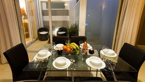 A dining table set for four with a fruit bowl, wine glasses, and cutlery.