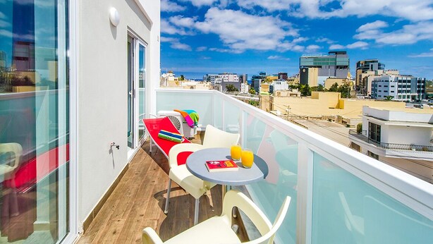 A balcony with a table, chairs, and a view of the cityscape. - Green 2: Two-Bedroom Apartment in St. Julian's (Swieqi)