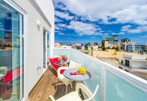 A balcony with a table, chairs, and a view of the cityscape.