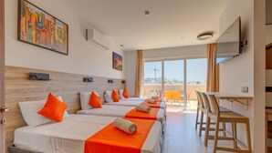 A hotel room with four beds, a dining area, and a large window offering a view of the city. - Red 6: Roof Top Studio Penthouse in St. Julian's (Swieqi)