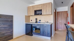 A modern kitchen with wooden cabinets, a built-in oven, and a dishwasher. - Black 8: Studio Apartment in St. Julian's (Swieqi)