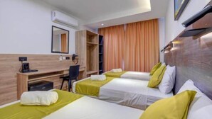A hotel room with two beds, a desk, a chair, a wardrobe, and a mirror. - Red 5: Studio Apartment in St. Julian's (Swieqi)