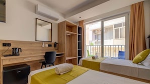 A hotel room with two beds, a desk, a chair, a minibar, and a balcony with a view. - Red 5: Studio Apartment in St. Julian's (Swieqi)
