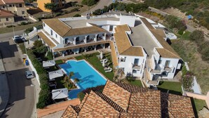 Un edificio grande y blanco con piscina, varios balcones y un patio.