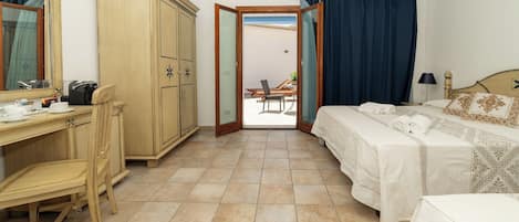 A hotel room with a bed, a desk, a chair, a wardrobe, and a view of the outside.
