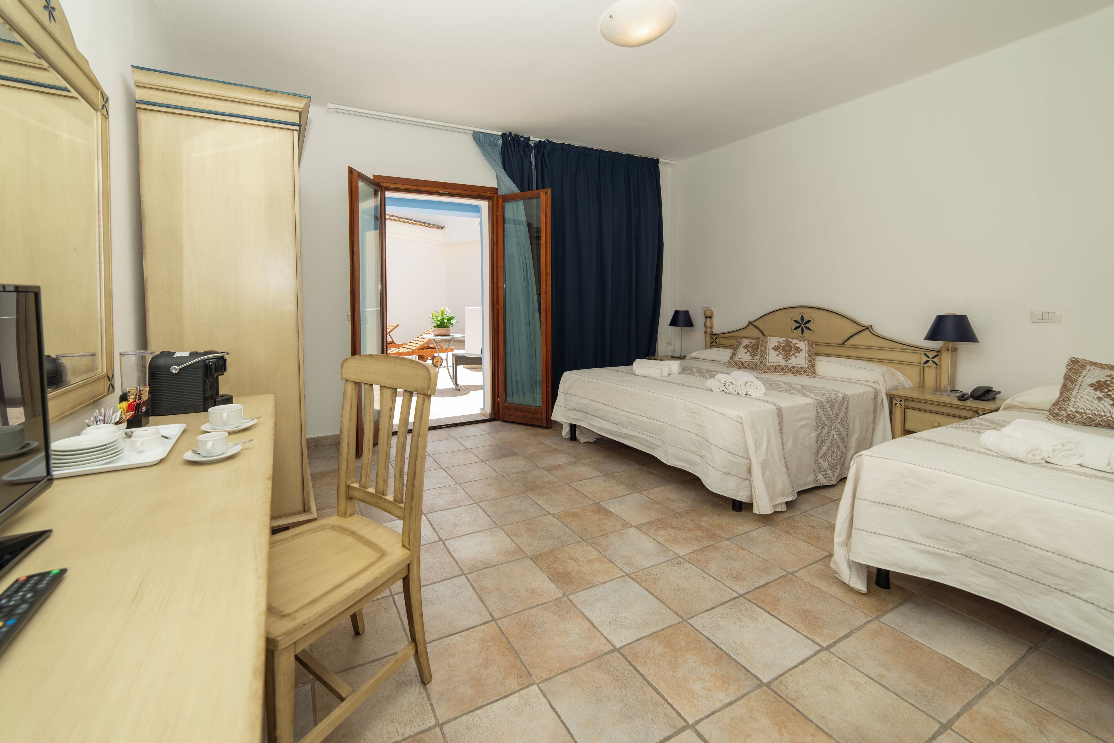 A hotel room with two beds, a desk with a computer, and a chair.