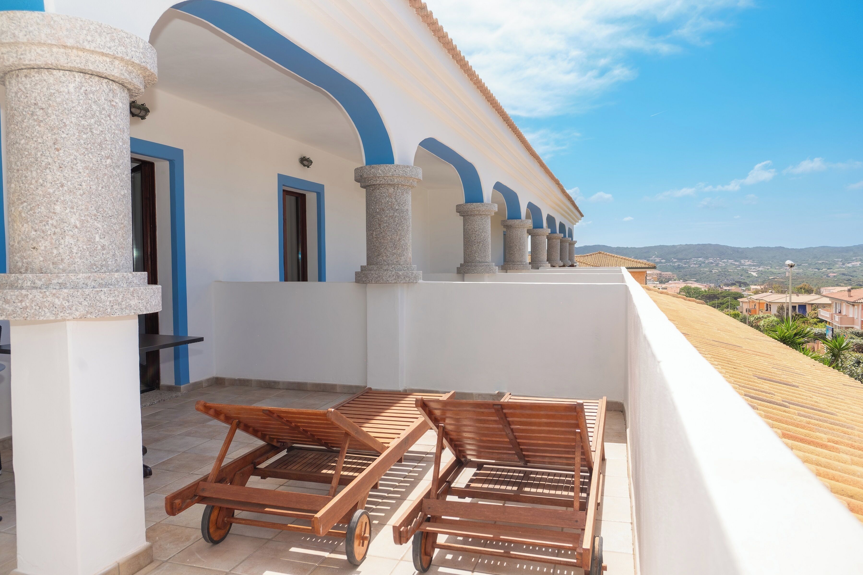 A balcony with wooden loungers and a view of the city.