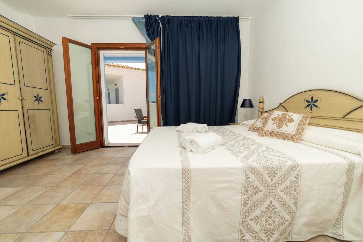 A bedroom with a bed, a wardrobe, and a door leading to a balcony.