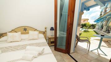 Ein Hotelzimmer mit Bett, Schreibtisch und Blick auf Pool und Garten.