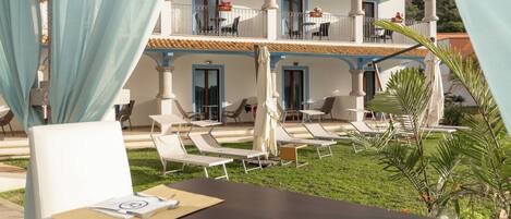 A hotel with outdoor seating, a pool, and a two-story building with balconies.